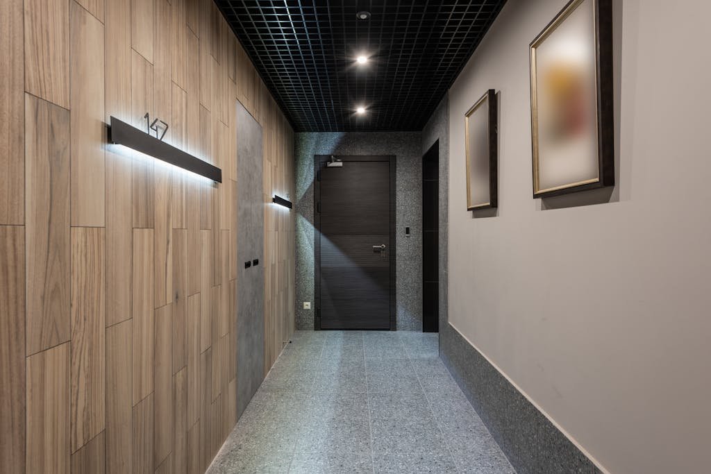 Interior of hallway with illuminated numbers of hotel rooms hanging on wall near doors